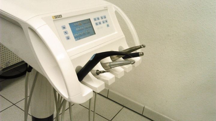 Ein Zahnarztstuhl mit Ger&auml;ten steht bereit, um Patienten zu helfen. Die Umgebung ist hell und klinisch.