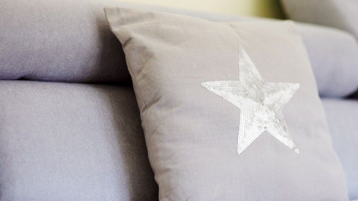 Ein grauer Kissenbezug aus einem alten T-Shirt mit einem wei&szlig;en Sternmuster ruht auf einem angeordneten Sofa.