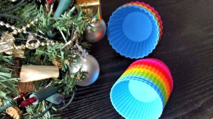 Bunte Silikonbackformen liegen neben festlichem Weihnachtsschmuck auf einem dunklen Tisch und warten auf den Einsatz.