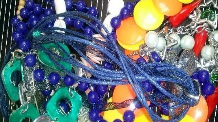 Bunte Ketten und Ohrringe liegen chaotisch auf einem Tisch und zeigen eine Vielzahl von Farben und Formen.