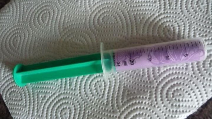 Eine Spritze mit gr&uuml;nem Griff und lila Kolben liegt auf einem K&uuml;chenpapier, bereit zum Einsatz in einem kreativen Geschenk.