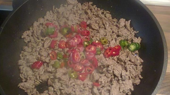 In einer Pfanne wird gebratenes Hackfleisch mit roten und gr&uuml;nen Paprika zubereitet, um eine leckere Gem&uuml;sebeilage zu kreieren.