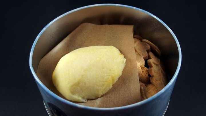 Kekse liegen in einer Dose, w&auml;hrend ein St&uuml;ck Butter darauf liegt, um die Pl&auml;tzchen weich zu halten.