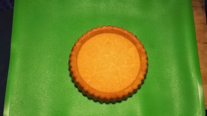 Ein runder, goldbrauner Tortenboden liegt auf einer gr&uuml;nen Oberfl&auml;che und wartet darauf, belegt und dekoriert zu werden.