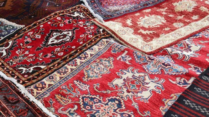 Bunte Teppichbr&uuml;cken liegen auf dem Boden, w&auml;hrend sie zur Reinigung vorbereitet werden, um ihre Farben und Muster hervorzuheben.