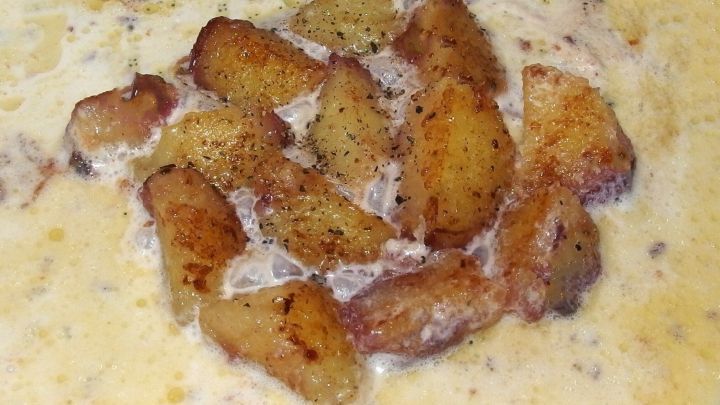 Die knusprigen Kn&ouml;delst&uuml;cke schwimmen in einer cremigen, veganen So&szlig;e und bilden ein herzhaftes Gericht.