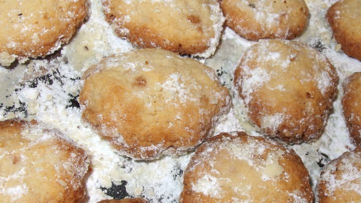 Zarte, frisch gebackene Pl&auml;tzchen liegen auf einem Backblech, bestreut mit Puderzucker in einer heimischen K&uuml;che.