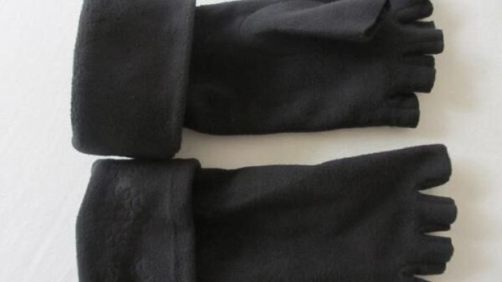 Schwarze Fleecehandschuhe liegen flach auf wei&szlig;em Hintergrund, zeigen abgeschnittene Finger und umgeschlagene B&uuml;ndchen.