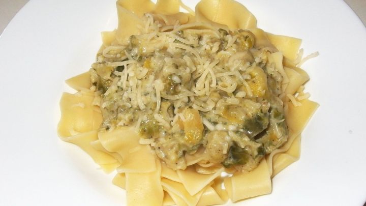 Eine Portion Pasta liegt auf einem wei&szlig;en Teller, bedeckt mit einer cremigen Rosenkohl-Sauce und K&auml;se, umgeben von einer neutralen K&uuml;chenszene.