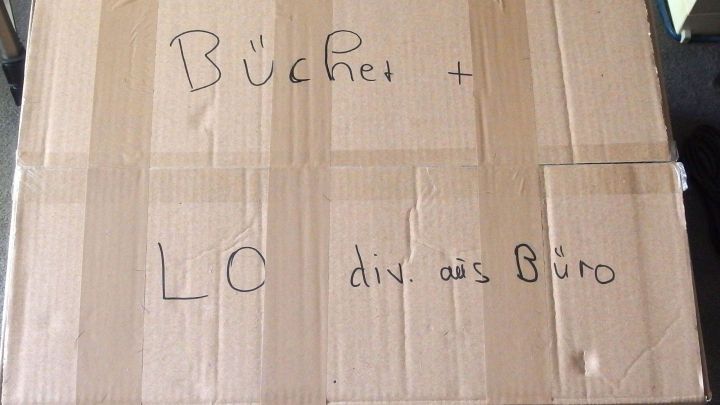 Ein Umzugskarton mit der Aufschrift "B&uuml;cher" und "L&ouml; div. aus B&uuml;ro" steht bereit, um das Packen zu erleichtern.