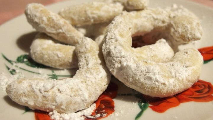 Auf einem Teller liegen mehrere Vanillekipferl, die mit Puderzucker best&auml;ubt sind, bereit zum Genie&szlig;en.