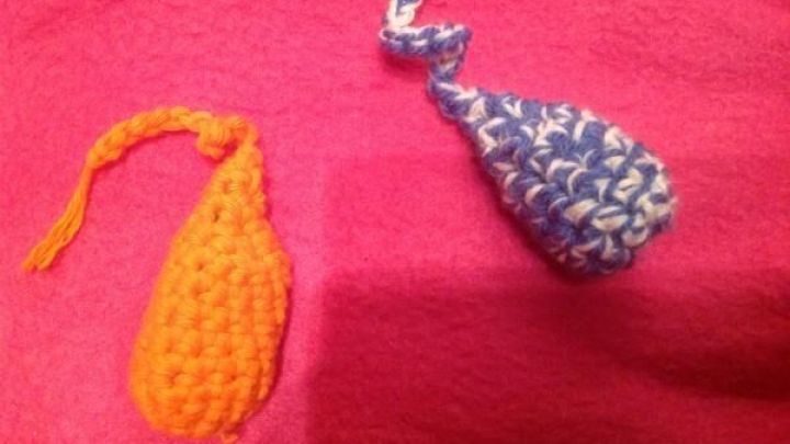 Geh&auml;keltes Katzenspielzeug in Form von zwei bunten Fischen liegt still auf einem pinken Stoff.