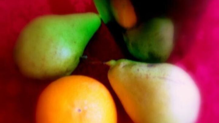 Birnen und eine orange Frucht liegen auf einem roten Tuch, w&auml;hrend sie auf eine Karamellso&szlig;e warten.