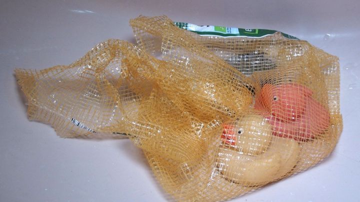 Nasses Badespielzeug liegt in einem Netz. Es wird zum Trocknen in einer Badewanne aufbewahrt, um Wasseransammlungen zu vermeiden.