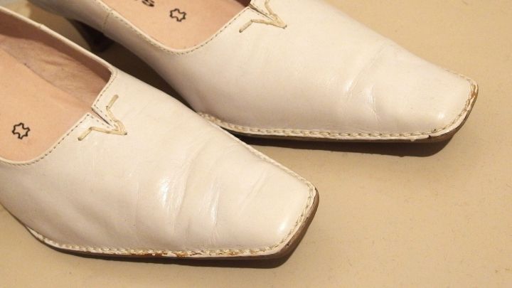 Wei&szlig;e Schuhe liegen auf einem hellen Untergrund und zeigen dunkle Streifen, die entfernt werden sollen.