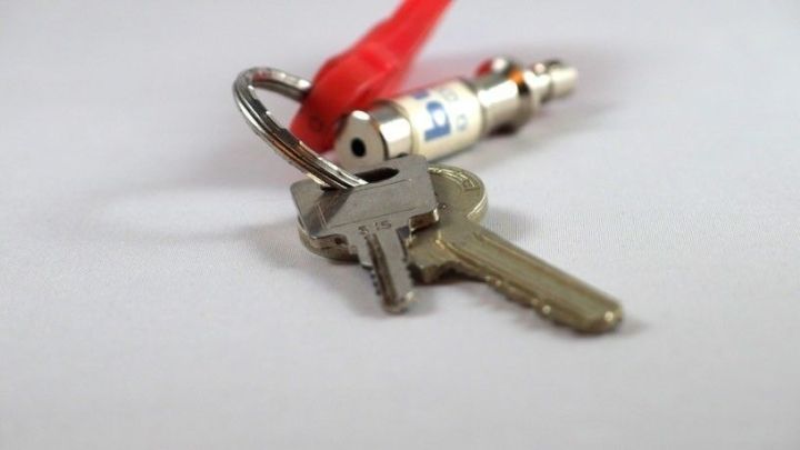 Ein Schl&uuml;sselbund mit zwei Schl&uuml;sseln liegt auf wei&szlig;em Hintergrund, erg&auml;nzt durch einen rot-wei&szlig;en Anh&auml;nger.