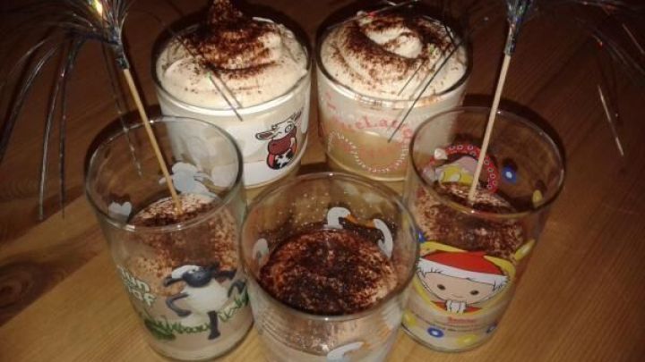 Gl&auml;ser mit Latte Creme, bestreut mit Kakaopulver, stehen auf einem Holztisch. Bunte Trinkhalme ragen aus den Gl&auml;sern.