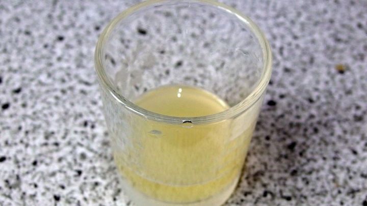 Ein Glas mit frischem Zitronensaft steht auf einer hellen, strukturierten Oberfl&auml;che, bereit zur Verwendung gegen &Uuml;belkeit.