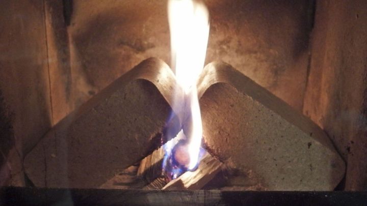 Ein Kaminglas wird gereinigt, w&auml;hrend das Feuer im Kamin flackert und eine warme Atmosph&auml;re schafft.