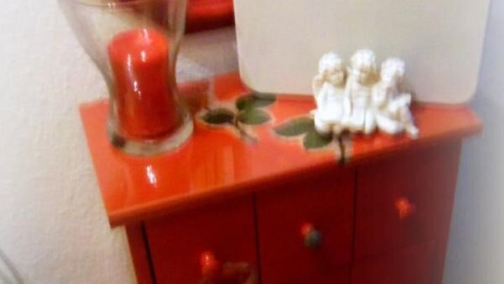 Ein roter Schrank steht im Flur, darauf liegen eine digitale Waage und Dekoration. Der Raum reflektiert einen pers&ouml;nlichen Stil.