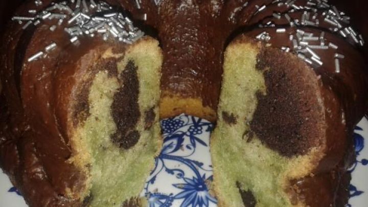 Kuchen zeigt eine angeschnittene Marmormischung aus Schokolade und Minze, dekoriert mit silbernen Streuseln auf einer blauen Platte.