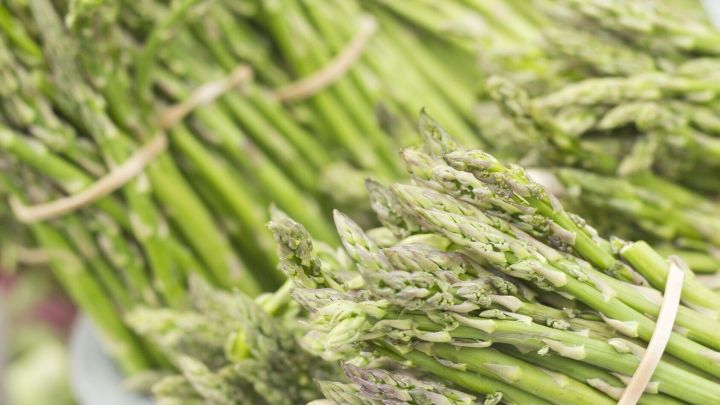 Frischer Spargel liegt geb&uuml;ndelt auf einem Tisch, bereit zum Kochen in Spargelfond, um den Geschmack zu intensivieren.