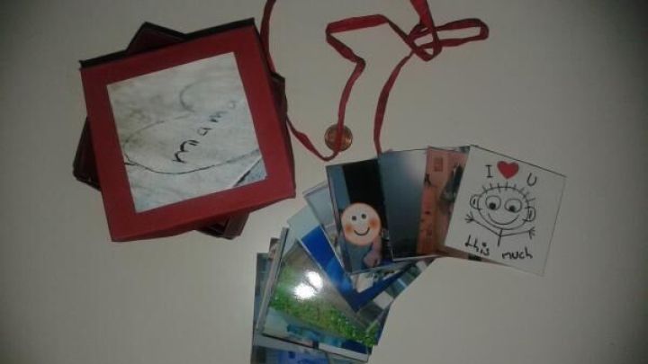 Ein rotes Schnappschuss-Sch&auml;chtelchen liegt offen, umgeben von verschiedenen Fotos, die Emotionen und Erinnerungen zeigen.