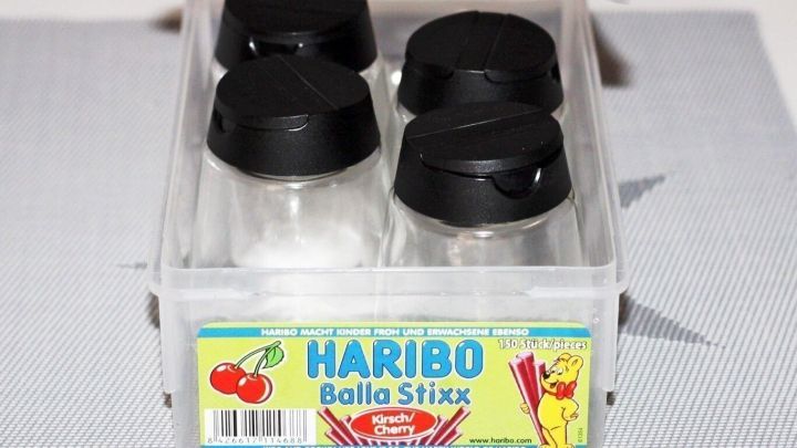 Die transparenten Vorratsdosen mit schwarzen Deckeln sind in einer klaren Box angeordnet, um Zutaten zu lagern.