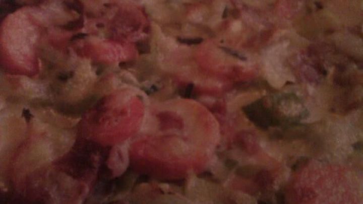 Eine gebackene M&ouml;hren Tarte liegt auf einem Blech, belegt mit geschnittenen M&ouml;hren, Porree und Schinkenw&uuml;rfeln.