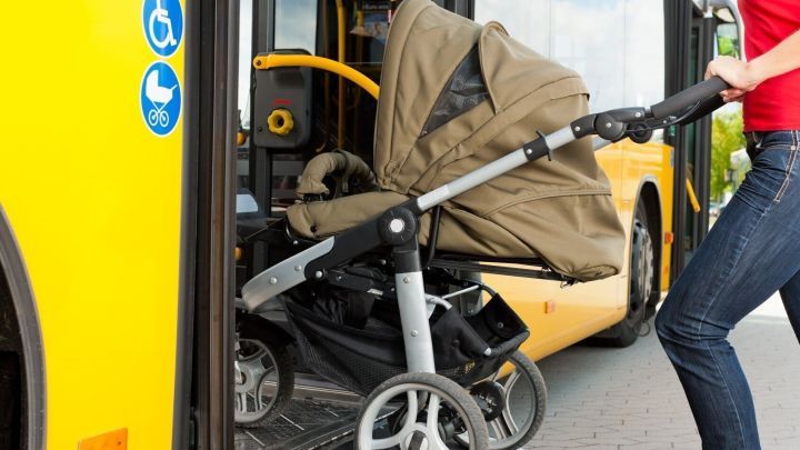 Ein Kinderwagen wird in einen gelben Bus geschoben, w&auml;hrend eine Person ihn sicher hineinschiebt, um unterwegs zu reisen.