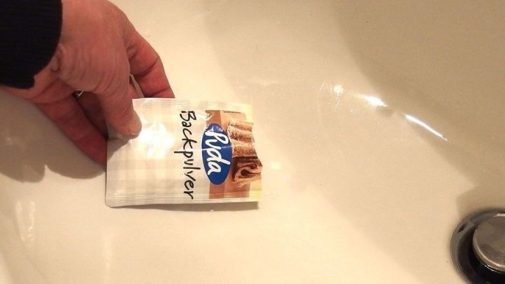 Eine Hand h&auml;lt ein Paket zum Entfernen von Ablagerungen und platziert es in ein Waschbecken.