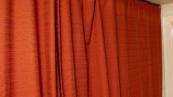 Ein roter Fl&auml;chenvorhang h&auml;ngt in einem Raum und bedeckt ein Fenster, um Licht zu d&auml;mpfen und Privatsph&auml;re zu bieten.