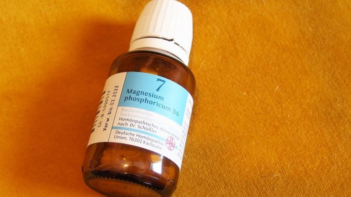 Eine braune Flasche mit einem wei&szlig;en Deckel steht auf einem orangefarbenen Untergrund, bereit zur Linderung von Kopfschmerzen.