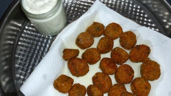 Linsenb&auml;llchen liegen auf einem K&uuml;chentuch, daneben ein Glas Joghurtdressing auf einem Tablett.