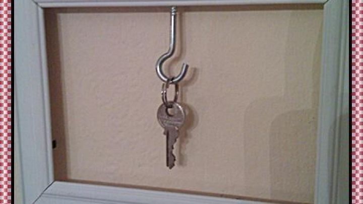 Ein wei&szlig;er Bilderrahmen h&auml;ngt an der Wand und h&auml;lt einen Schl&uuml;ssel an einem Haken, ideal f&uuml;r die Schl&uuml;sselaufbewahrung.