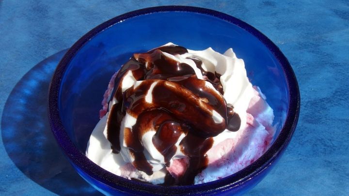 Eine Sch&uuml;ssel mit Sahne und Schokoladensauce steht auf einem blauen Tisch, ideal zum Genie&szlig;en beim Kalorien z&auml;hlen.