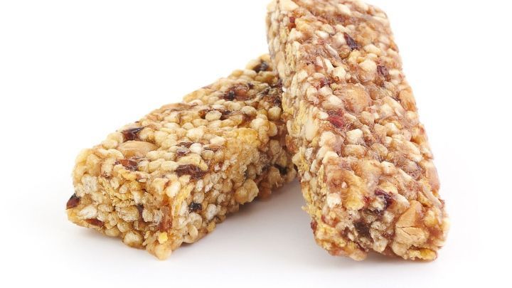 Zwei M&uuml;sliriegel liegen &uuml;bereinander, bereit zum Verzehr, in einem hellen, neutralen Umfeld, das ihre Textur hervorhebt.