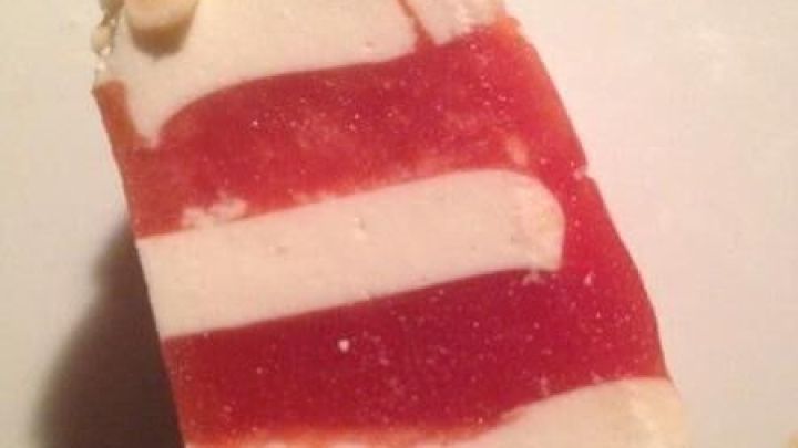 Eine schicke Terrine mit roten Schichten und Wei&szlig;k&auml;se, dekoriert mit Pinienkernen, auf einem Teller pr&auml;sentiert.