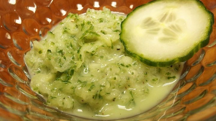 Ein Gurkensalat mit Milch in einer Sch&uuml;ssel, garniert mit einer Gurkenscheibe, erfrischend und gr&uuml;nlich-cremig.