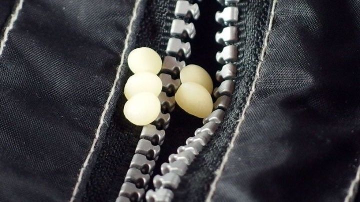 Ein Rei&szlig;verschluss steckt zwischen zwei Stoffschichten. Bienenwachs wird angewendet, um ihn wieder leichtg&auml;ngig zu machen.