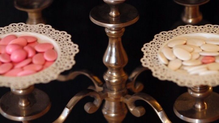 Ein eleganter Kerzenleuchter dient als Etagere, mit bunten S&uuml;&szlig;igkeiten auf verzierten Tellern, dekoriert mit Lavendel.