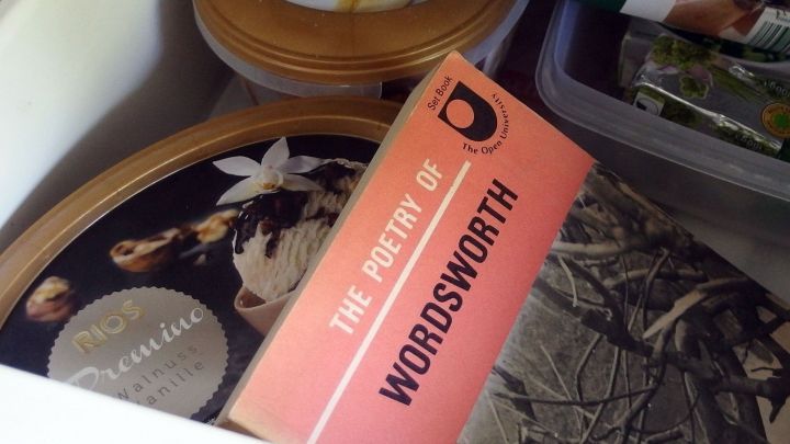 Ein alter, muffiger Buchr&uuml;cken liegt neben runden Dosen in einer Schublade, umgeben von verschiedenen farbigen Gegenst&auml;nden.