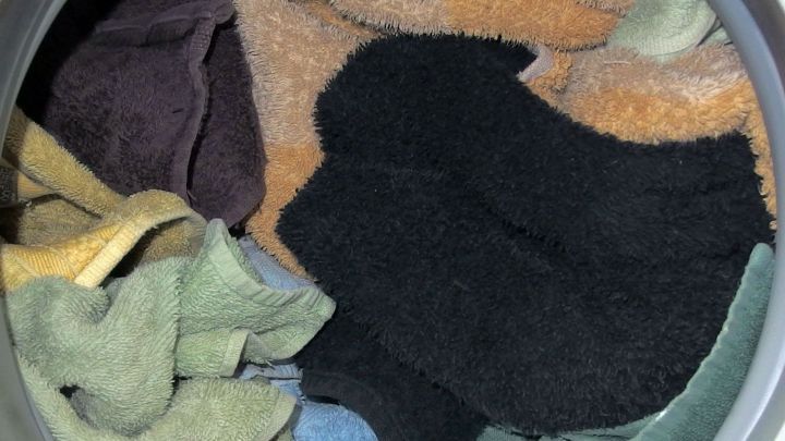 Nasse Handt&uuml;cher liegen zusammen mit trockenen T&uuml;chern in der trommelf&ouml;rmigen &Ouml;ffnung eines Trockners.