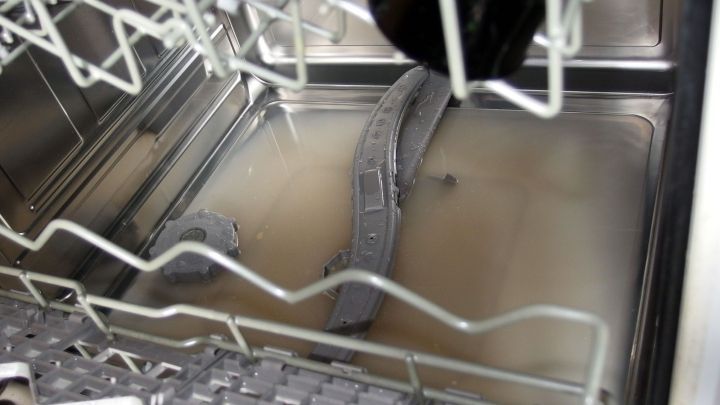 Eine Sp&uuml;lmaschine steht offen und zeigt tr&uuml;bes Wasser im Innenraum, das nicht abgepumpt wurde.