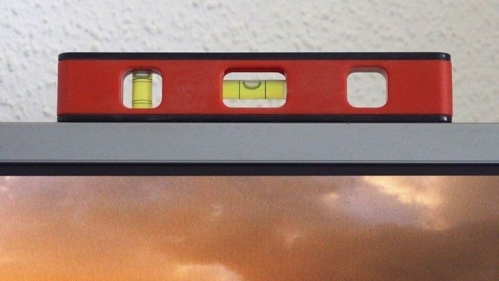 Eine Wasserwaage liegt auf einem Fernseher und zeigt die Ausrichtung, um Bilder richtig aufzuh&auml;ngen.