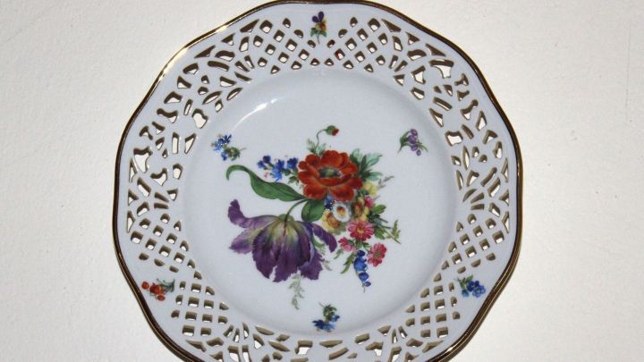 Ein dekorativer Teller mit Blumendekor h&auml;ngt an einer Wand, um den Raum mit einem charmanten Accessoire zu versch&ouml;nern.