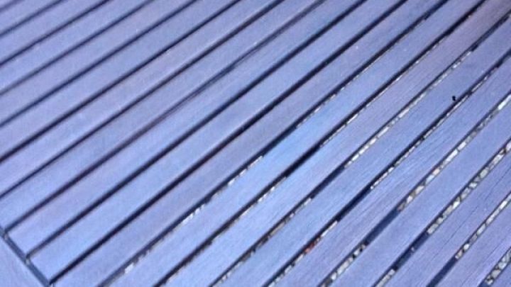 Ein Holztablett mit schmalen Lamellen liegt auf einer Fl&auml;che aus Kies, ideal f&uuml;r die Pflege von Holzgartenm&ouml;beln.