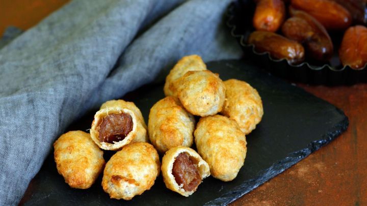 Gef&uuml;llte Datteln liegen auf einem schwarzen Teller, w&auml;hrend ungef&uuml;llte Datteln daneben in einer Schale liegen.