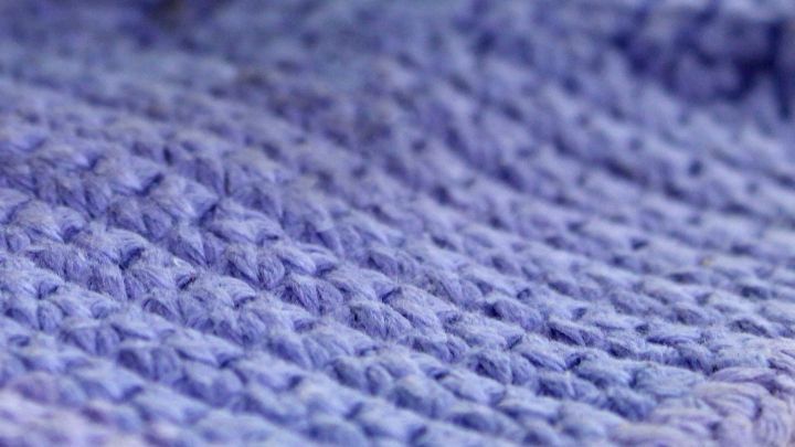 Ein gestrickter, lila Schal liegt sanft auf einer Oberfl&auml;che, bereit zum Verschenken oder f&uuml;r eine nette Verpackung.