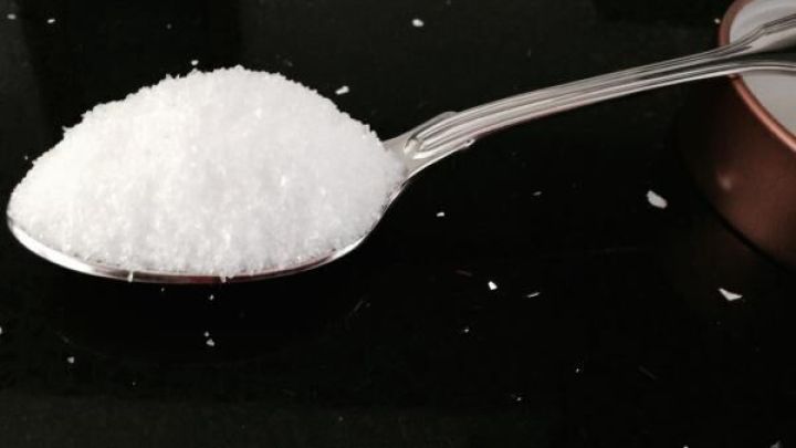 Ein L&ouml;ffel mit Salz liegt auf einer dunklen Oberfl&auml;che, bereit f&uuml;r die Buntw&auml;sche anstelle von Colorwaschmittel.